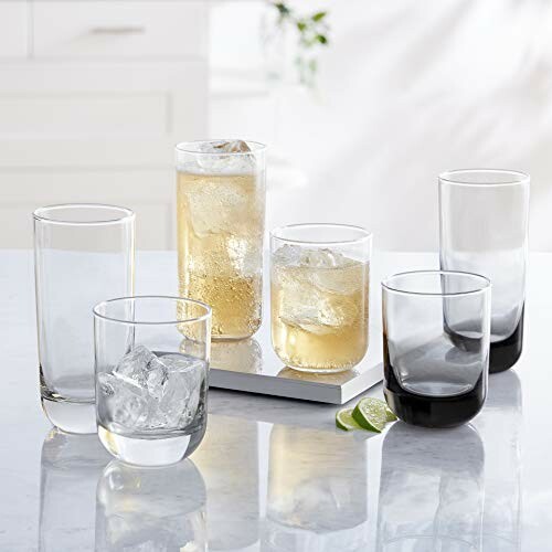 Assorted drinking glasses with beverages and ice on a table.