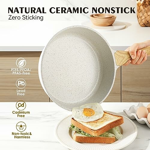 Hand holding ceramic nonstick frying pan above sandwich with fried egg.