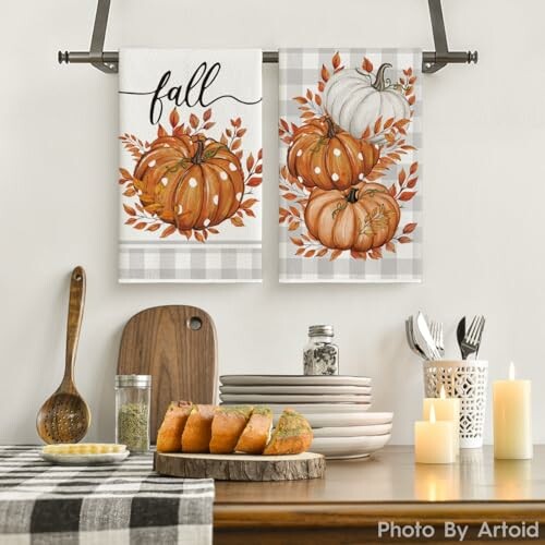 Fall-themed kitchen decor with pumpkin towels, candles, and bread.