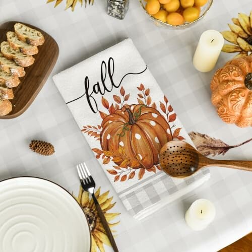 Fall-themed table setting with pumpkin towel and autumn decor.