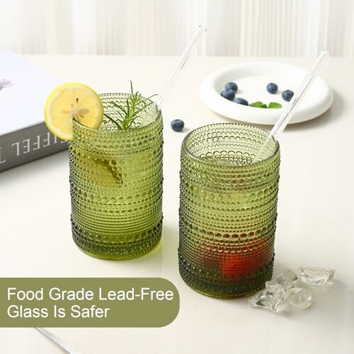 Two green textured glasses with lemon and herbs.