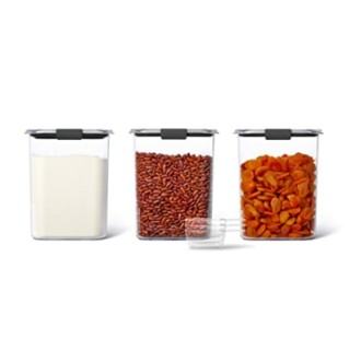 Three clear storage containers with black lids filled with flour, red beans, and dried apricots.