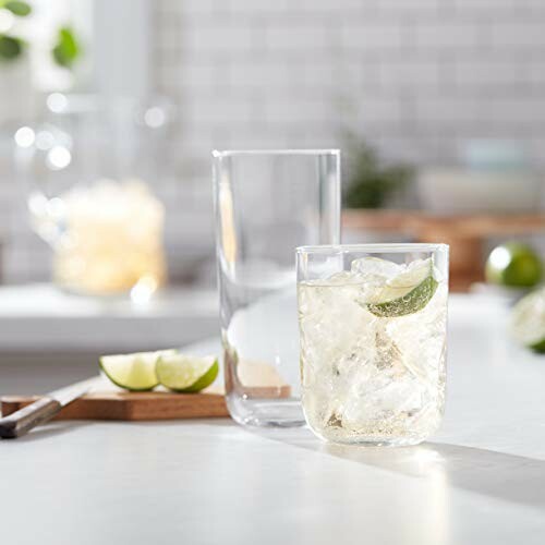 Glass of iced drink with lime slices on a table.