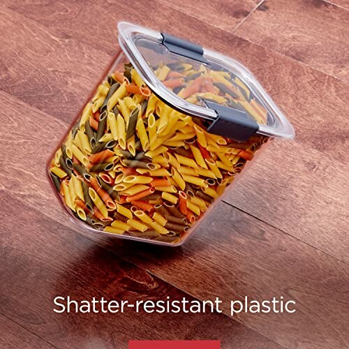 Plastic container filled with colorful pasta on wooden surface.