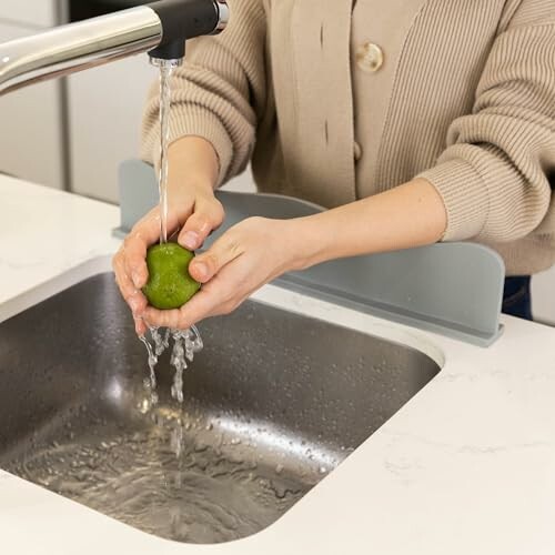 Person washing a lime under a kitchen faucet